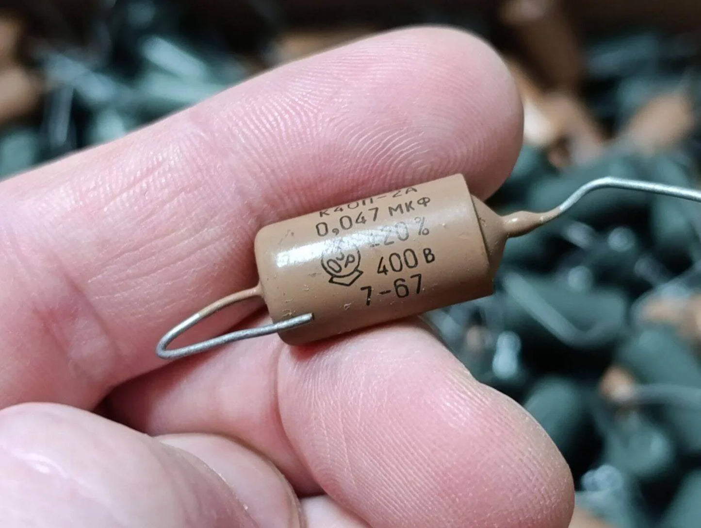 Close-up of a K40P-2A .047uF 400V capacitor held by a hand, showcasing vintage design and markings.