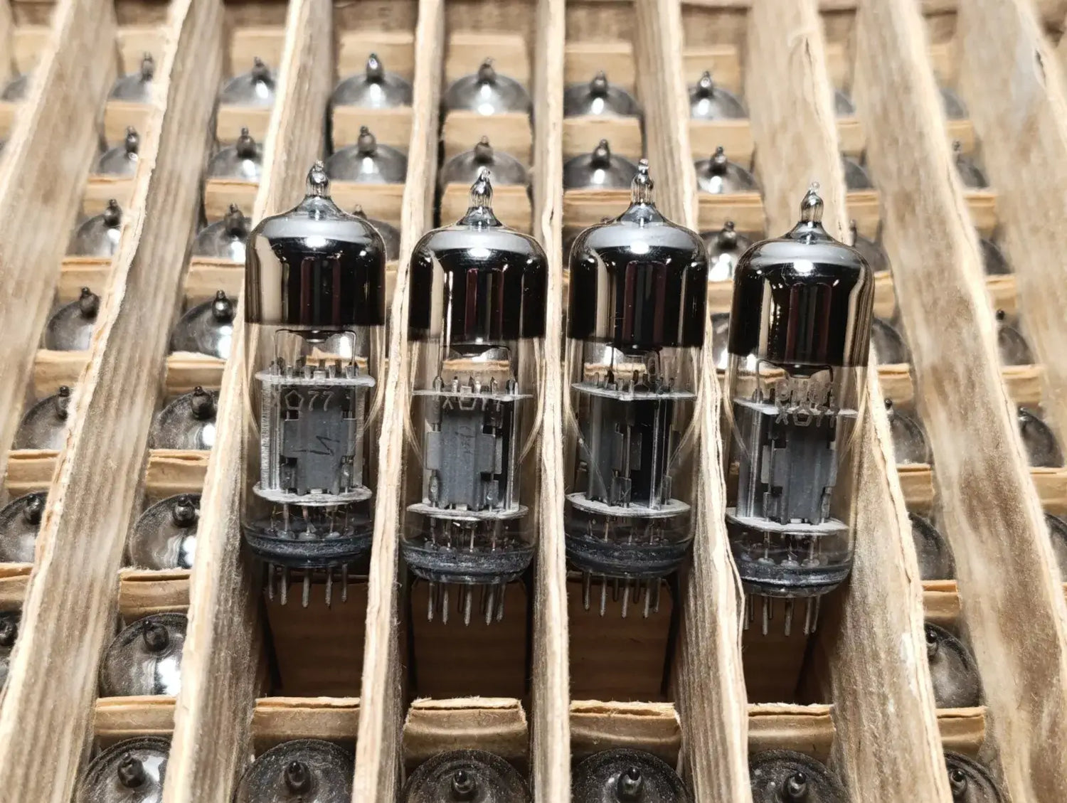 Close-up of triodes in a row, showcasing their glass and metal design for electronics history and innovation.
